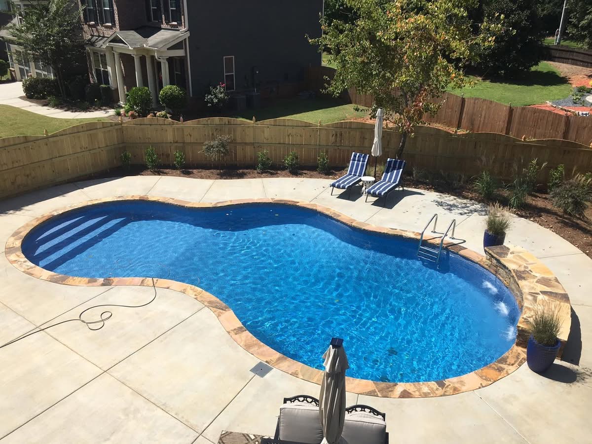 Finished freeform vinyl pool with a stacked-stone waterfall feature in a North Georgia backyard